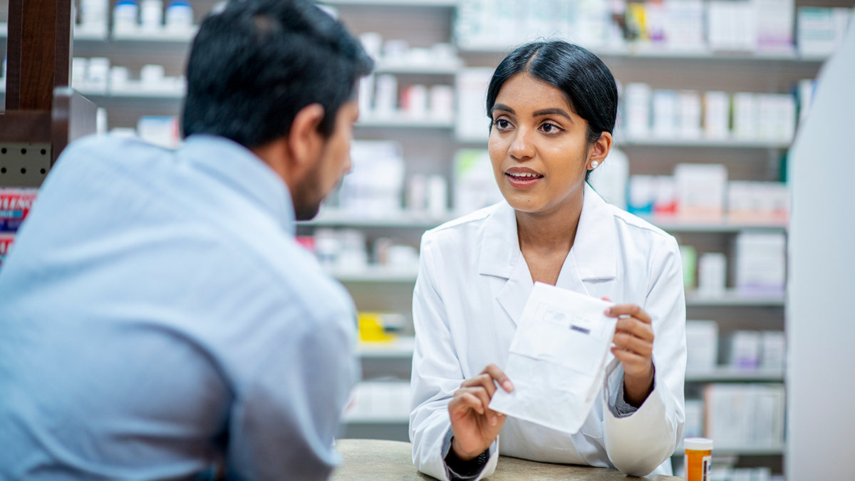 A customer listens carefully to a pharmacist's advice concerning their prescription.