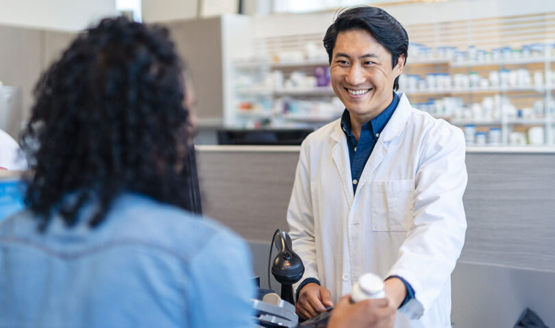 Male pharmacist assisting woman with prescription medication