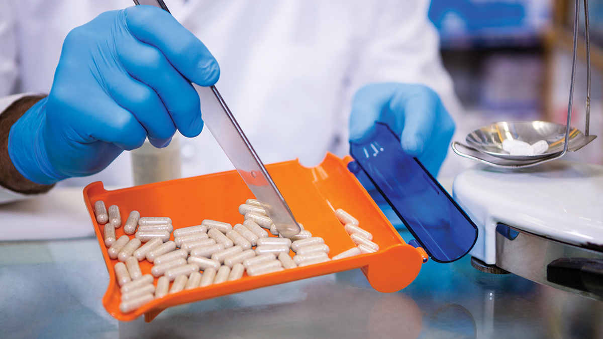 Pharmacist putting pills in container at pharmacy