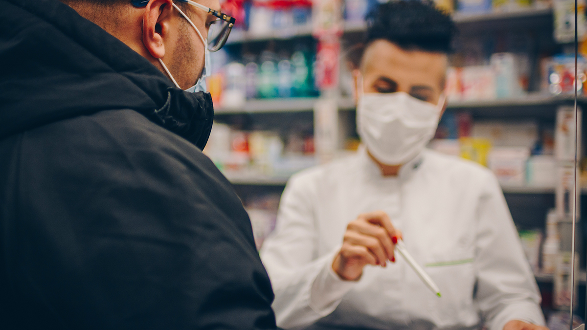 Pharmacist with mask talking to patient