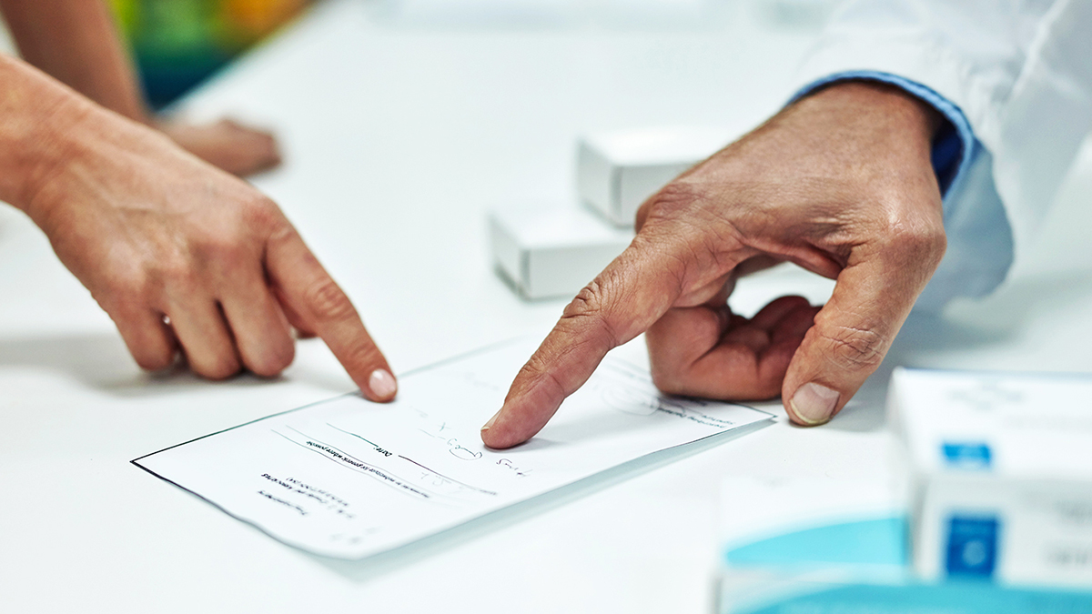 pharmacist and patient pointing at prescription