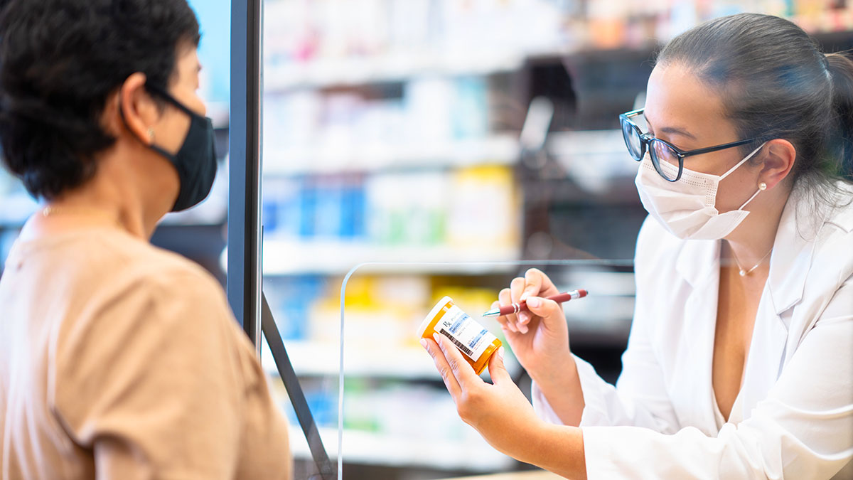 pharmacist talking to patient, both wearing masks