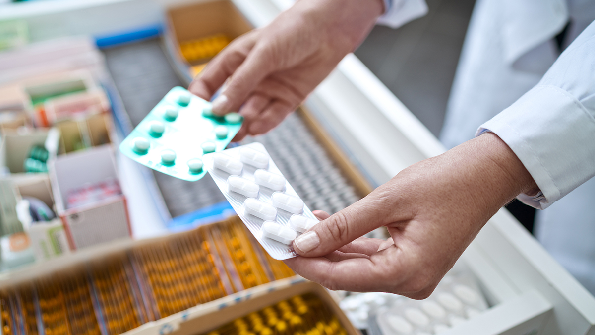 Pharmacists holding pills in hands above drawer with medicines. Close up of hands, unrecognizable person.