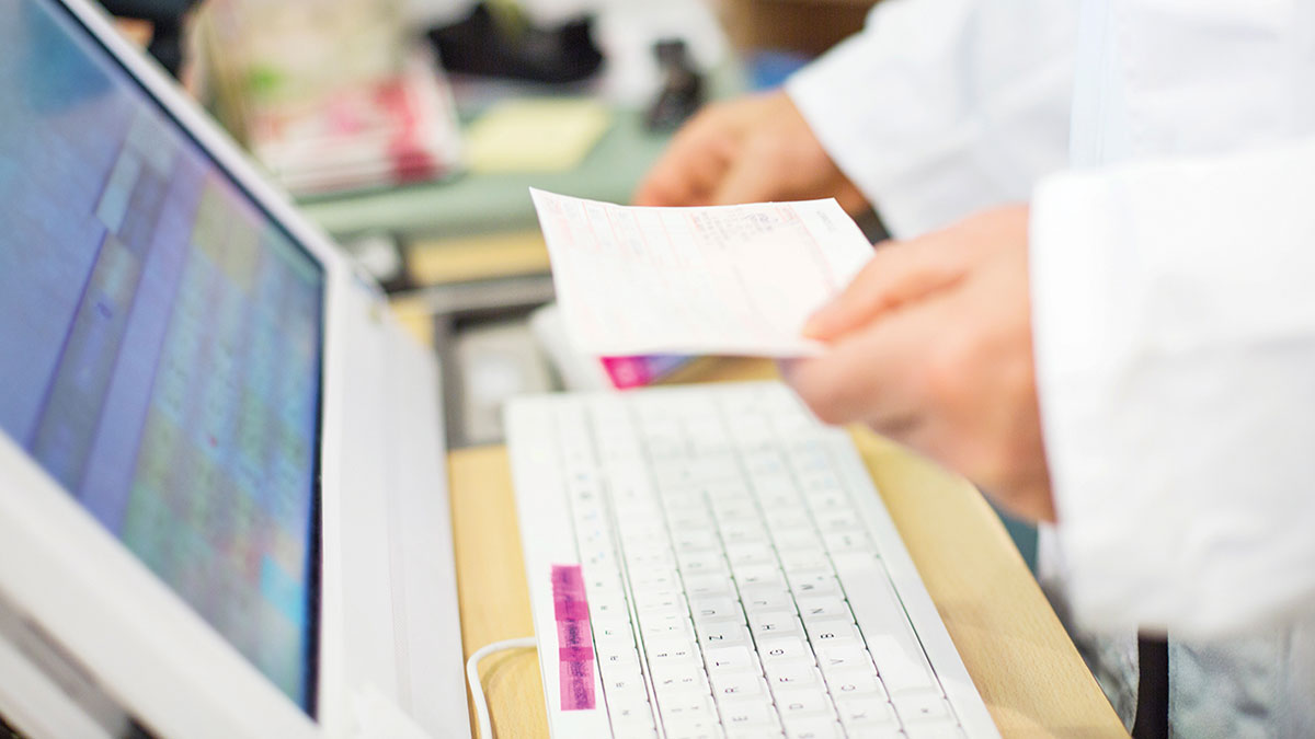 pharmacist with prescription at computer