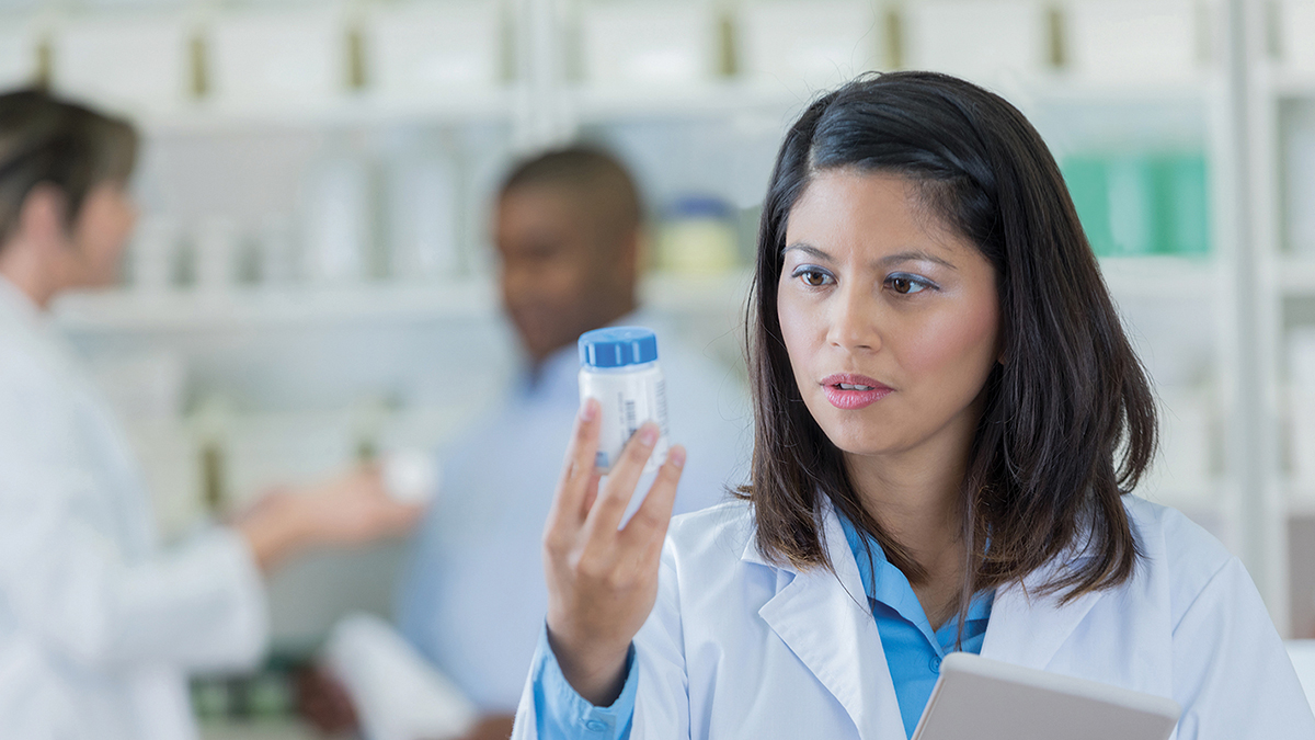 pharmacist looking at pill bottle
