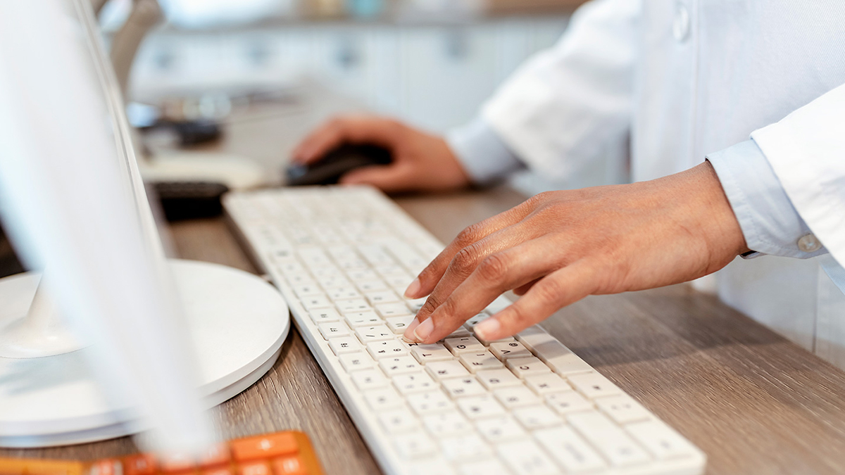 Closeup of pharmacist's hands typing on a computer