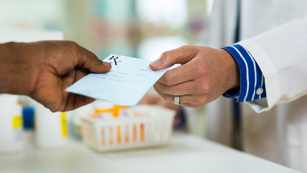 patient passing a prescription to pharmacist