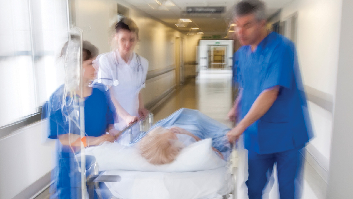 patient on stretcher or gurney being pushed at speed through a hospital